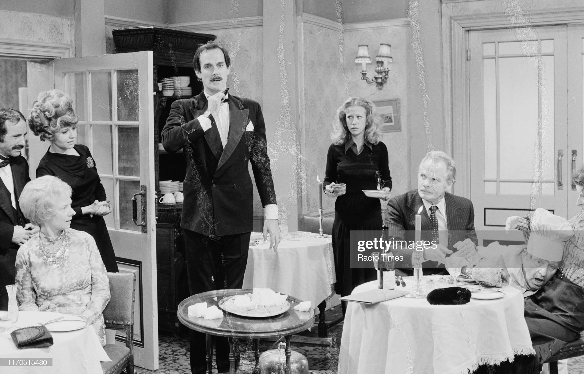 Actors (L-R) Andrew Sachs, Betty Huntley-Wright, Prunella Scales, John Cleese, Connie Booth, Allan Cuthbertson and Steve Plytas in a scene from episode 'Gourmet Night' of the BBC television sitcom 'Fawlty Towers', September 6th 1975. (Photo by Don Smith/Radio Times via Getty Images)
