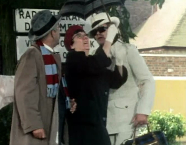 The gang sheltering under an umbrella, on location