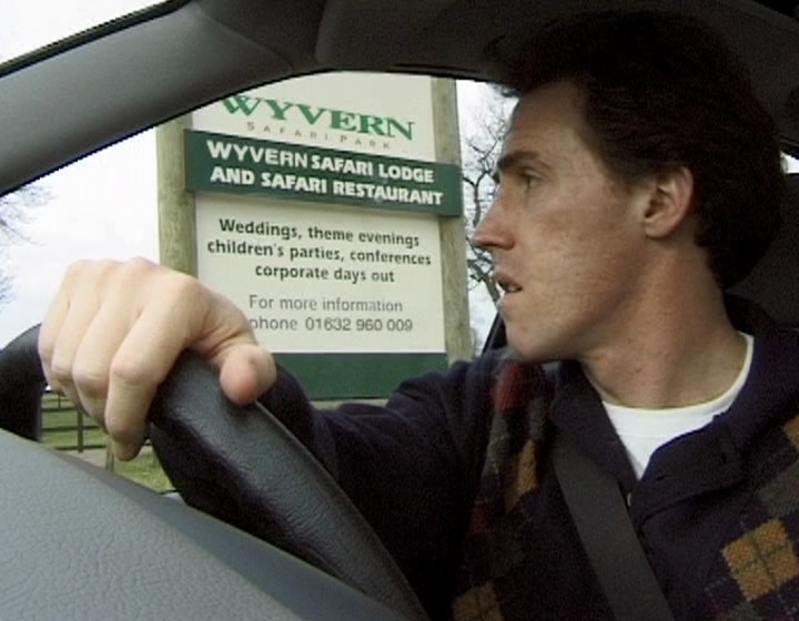 Keith, sitting outside a sign for Wyvern Safari Park