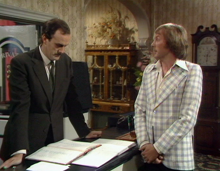 Fawlty Towers: John Cleese as Basil, and Trevor Adams as Alan. Although the main point here is that the set in both pictures is extremely similar.