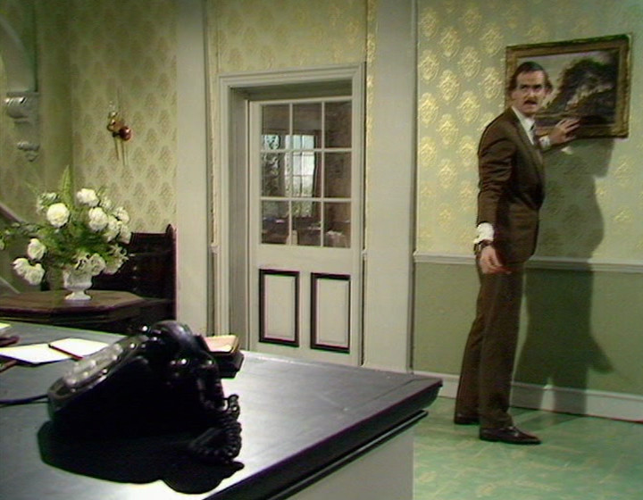 Fawlty Towers: John Cleese as Basil, and of course nobody sitting in the lobby, because that's not how the show worked